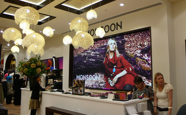 Graphics featuring a model in Monsoon behind tills