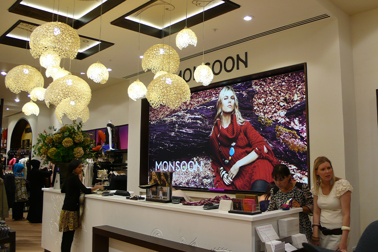 Graphics featuring a model in Monsoon behind tills